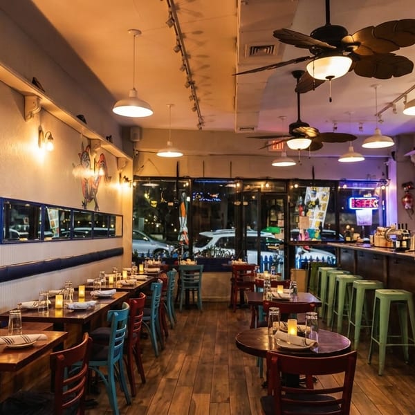 A vibrant restaurant interior with colorful murals, wooden tables, and a long bar with stools.